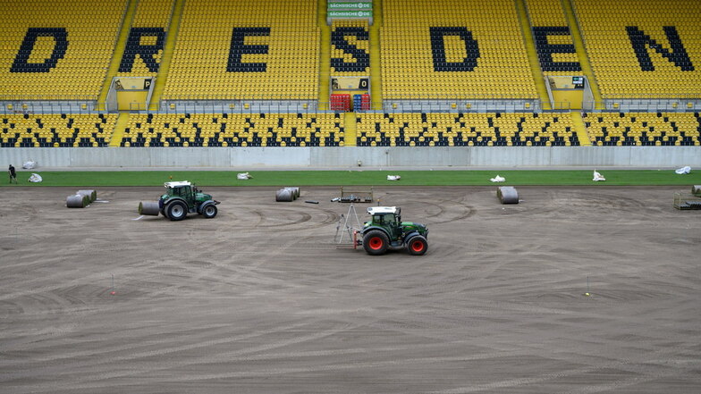 Traktoren verteilen am Mittwoch die 150 Kilo schweren Rollrasen-Bahnen auf der Spielfläche des Harbig-Stadions.