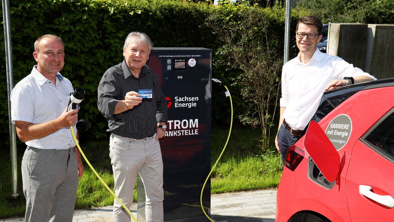 Der Nünchritzer Bürgermeister Gerd Barthold (Mitte) sowie Tilo Kadner (li.) und Gunnar Schneider (re.) von der Sachsen-Energie AG nehmen die Strom-Tankstelle auf dem Seußlitzer Schloss-Parkplatz in Betrieb.