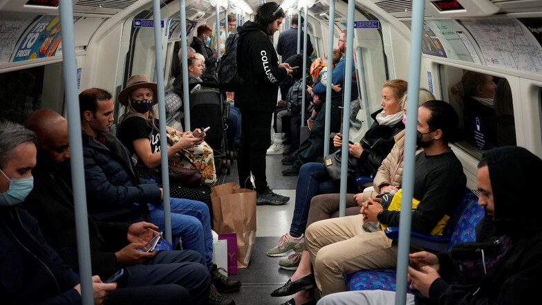 Pendler sitzen zum Teil mit und ohne Mund-Nasen-Schutz in einer Londoner U-Bahn.