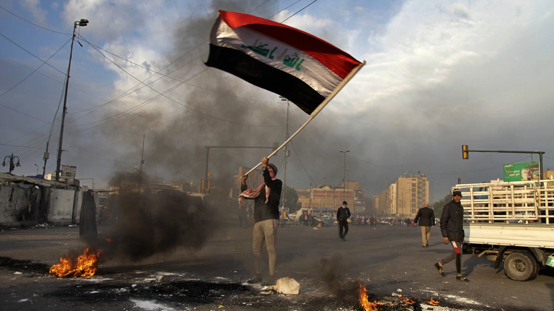 Gewaltakt auf Gewaltakt: Ein Demonstrant schwenkt bei einem Protest gegen den iranischen Raketenangriff auf US-Stützpunkte in Bagdad eine irakische Flagge.