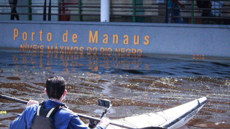 Ein Mann paddelt mit seinem Kayak im Hafen von Manaus.