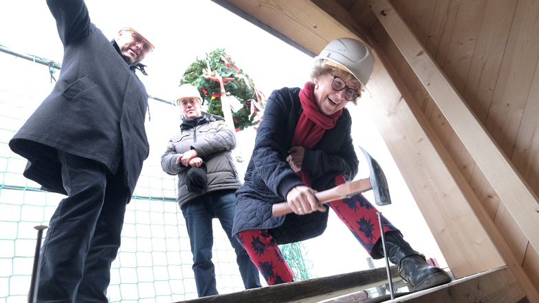 SEEG-Geschäftsführerin Birgit Richter übernimmt es, den traditionellen letzten Nagel in einen Dachbalken einzuschlagen. In Hintergrund der Meißner Architekt Dr. Knut Hauswald.