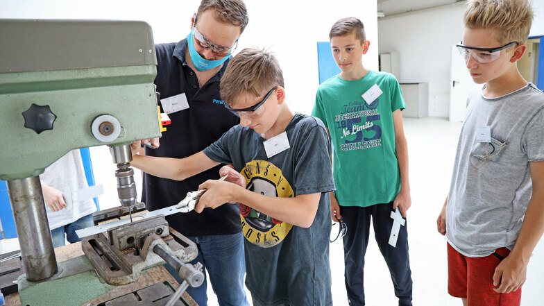 Unter Anleitung von Peter Kohlstrunk bearbeiten Riesaer Jugendliche in der Offenen Werkstatt Metallteile für die Design-Lampe. "Mit Metall habe ich noch nicht so oft gearbeitet, das ist cool", sagt der 14-jährige Aron (r.).