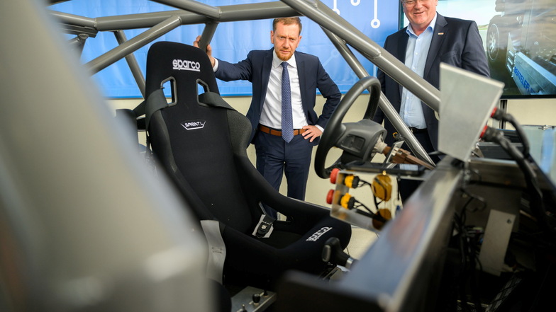 Sachsens Ministerpräsident Michael Kretschmer (CDU, links), sieht gemeinsam mit Bosch-Konzernchef Stefan Hartung vor der Dresdner Chipfabrik ein Fahrzeug mit viel Bosch-Elektronik an.