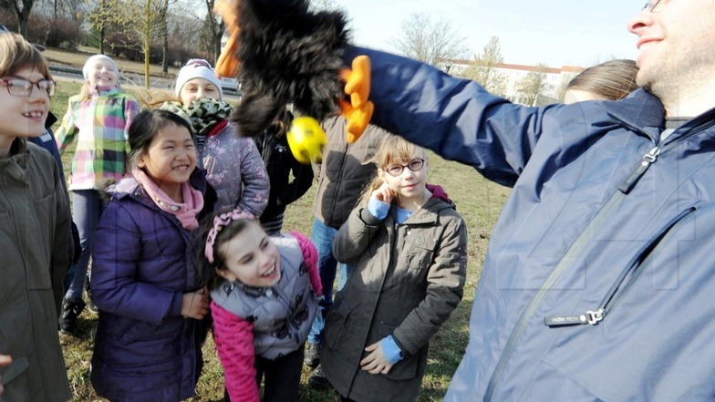 Spielmobil-Mitarbeiter André Krahl zeigt den Ferienkindern den Raben, das Maskottchen.
