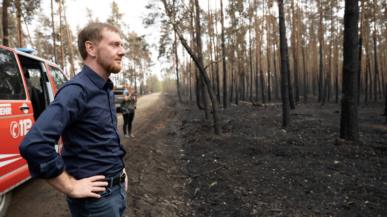 Michael Kretschmer begutachtet die Schäden in dem an Brandenburg angrenzenden Waldbrandgebiet in Nordsachsen.