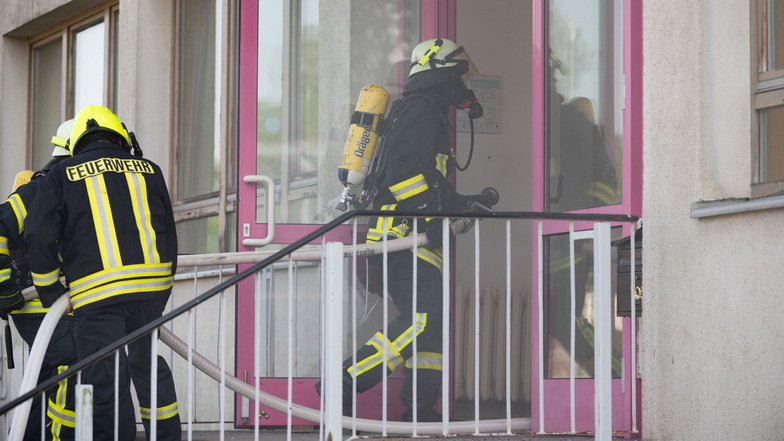 Die Feuerwehrleute und Frauen betreten in Schutzausrüstung und mit Sauerstoffversorgung, sowie Wasserschläuchen, das Gebäude.
