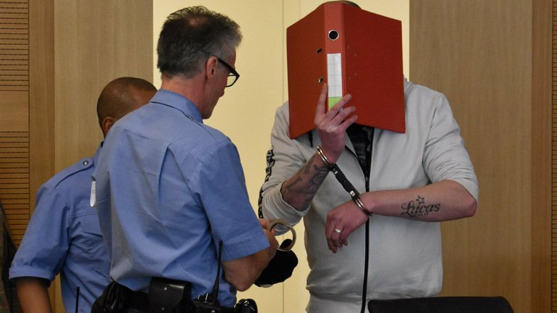 Sebastian T. wird am Landgericht Dresden zur Verhandlung vorgeführt. Er verbirgt sein Gesicht hinter einem roten Aktenordner.