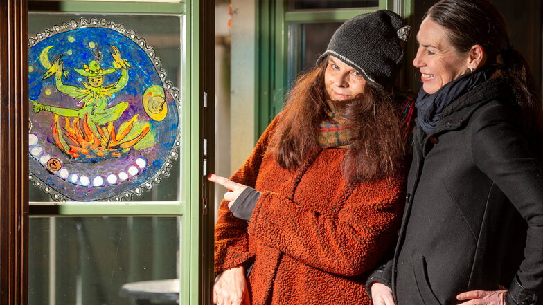 Welches Märchen stellt das Fensterbild dar? Die Künstlerin Dorothea Kuhbandner (l.) zeigt mit der Gastronomin Mandy Hähnel auf eines ihrer Motive, die es auf dem Märchenpfad zu erraten gilt.