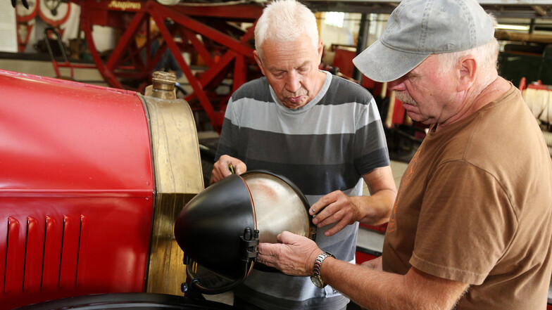 Gerd Langer (links) und Frank Zacharias reparieren eine Frontlampe am Oldtimer von 1920.