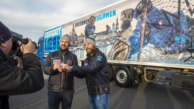 Die Spieler Florian Proske (re.) und Steven Rupprich posieren auf dem Gelände des Logistik-Unternehmens Dachser in Radeburg vor einem neuen Truck, der auf seiner Außenfläche für die Dresdner Eislöwen wirbt.