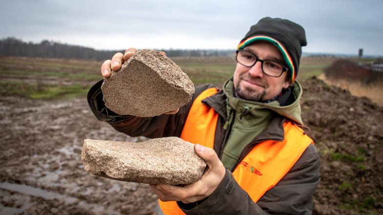 Ausgrabungsleiter Thomas Lukas zeigt auf dem künftigen Bauplatz von Karls Erlebnis-Dorf die Bruchstücke von Mahlsteinen aus der Steinzeit, die gefunden wurden.