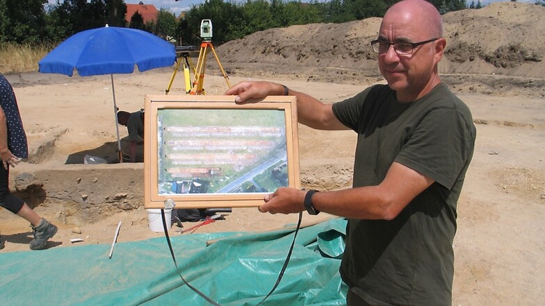 Grabungsleiter Olaf Ullrich zeigt die Drohnenaufnahme mit den Suchstreifen.