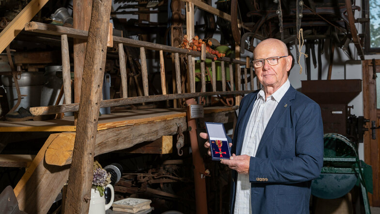 Kurt Weißhaupt steht mit seinem Bundesverdienstorden in der Museumsscheune in Rathewalde, die der selbst mit aufgebaut hat.