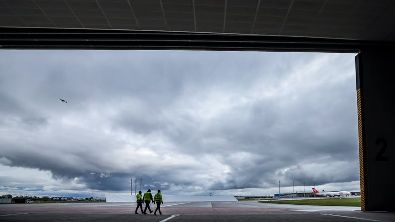 Flughafenmitarbeiter und der  Fluglärmschutzbeauftragte  gehen durch die Triebwerksprobelaufhalle am Flughafen Leipzig/Halle.
