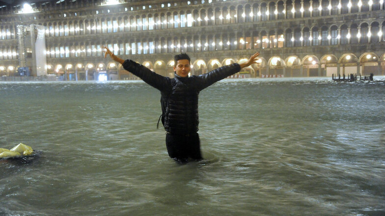 Ein Mann steht im Hochwasser auf dem überschwemmten Markusplatz. 