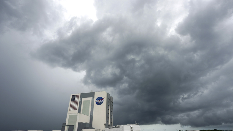 Regenwolken steigen über dem Vehicle Assembly Building des Kennedy Space Center auf, während eine SpaceX "Falcon 9"-Rakete an der Startrampe 39A steht.