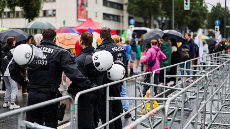 Drei Polizisten beobachten etwa 150 Demonstranten hinter einer Absperrung an der Grugahalle in Essen, in der der AfD-Bundesparteitag fortgesetzt wird.