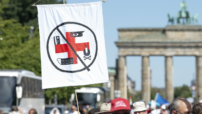 Eine Fahne, auf der Symbole aus einem Roten Kreuz ein Hakenkreuz formen, zeigt dieser Teilnehmer. 