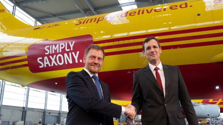 Der DHL-Vorstandsvorsitzende Tobias Meyer (r.) und Sachsens MP Michael Kretschmer  besiegeln die Vertragsverlängerung für das Frachtzentrum am Flughafen Leipzig.