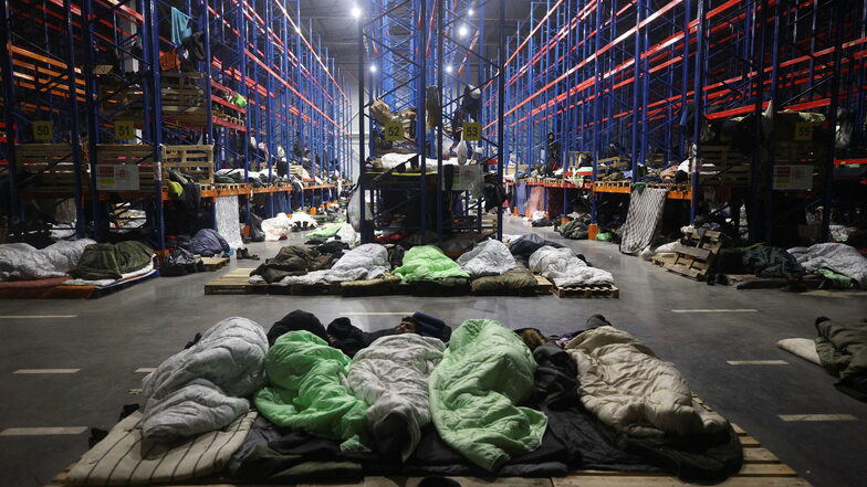 In Belarus schlafen Migranten nahe der polnischen Grenze in Schlafsäcken auf Paletten in einem Logistikzentrum. Angesichts der Lage stockt Sachsen seine Heimkapazitäten auf.