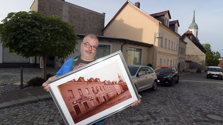 Holger Hummitzsch zeigt ein historisches Foto vom Roßweiner Kreuzplatz. Das Haus, in dem er eine Tagespflege eröffnen möchte, steht hinter der früheren Gaststätte „Deutsches Haus“.