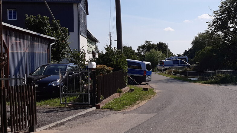 Vor einem Grundstück in Saalbach sind mehrere Polizeifahrzeuge zu sehen.