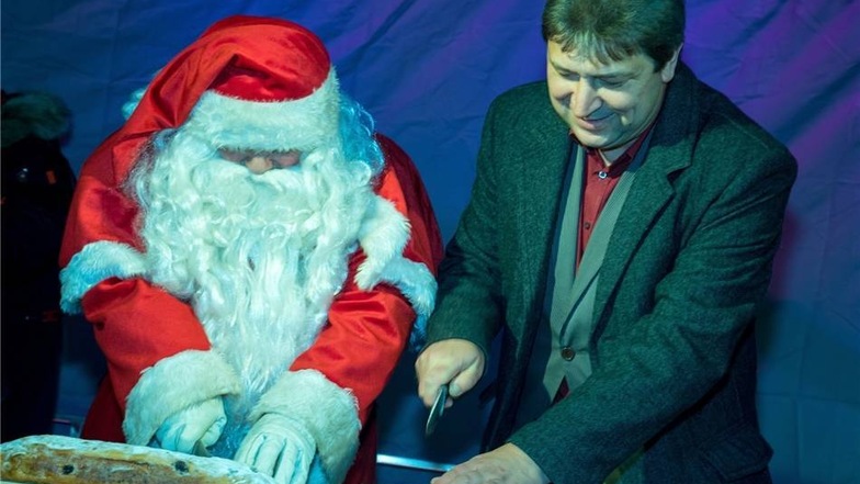 Hand in Hand arbeiten der Weihnachtsmann und Oberbürgermeister Holm Große beim Stollenanschnitt.