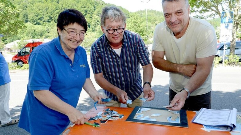Erster Kontrollpunkt am Weißeritzpark in Freital: Elke Tzschöckell stoppt die Zeit, in der Andreas Teuscher (links) und Norbert Holst ein Puzzle legen.