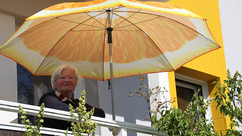 Die 78-jährige Edeltraud Tentschert genießt den Ausblick von ihrem Balkon und freut sich über die frisch gemalerte Fassade. Sie hat extra einen farblich dazu passenden neuen Sonnenschirm gekauft.