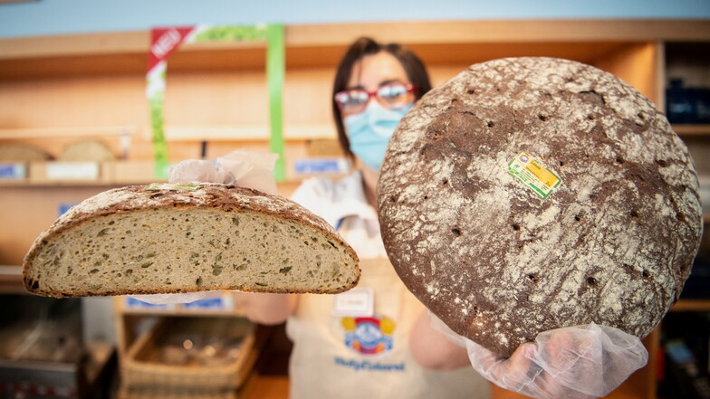 Eine Mitarbeiterin einer Bäckereifiliale der Kette Hofpfisterei hält einen Laib vom Brot ·Sonne· in den Händen. Die Bäckereikette Hofpfisterei hält die Rechte an der Marke "Sonne".
