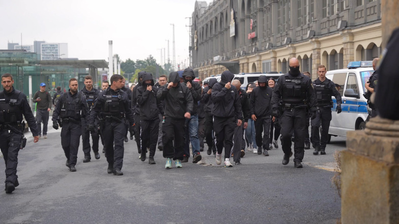 Eine Gruppe Rechtsextreme läuft am Dresdner Hauptbahnhof entlang. Die Polizei stoppt sie.
