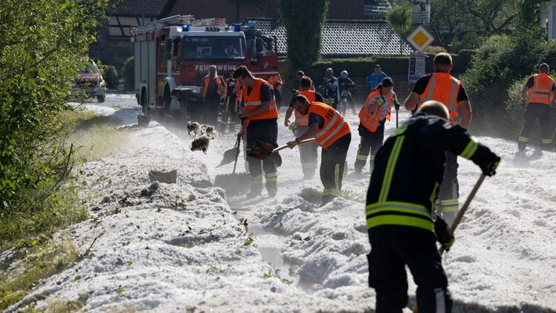 Einsatzkräfte räumen eine Straße im Hildburghausener Ortsteil Weitersroda: Innerhalb einer Viertelstunde überfluteten hier große Hagelkörner Straßen.