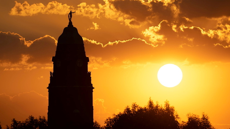 Der Dresdner Rathausturm zeichnet sich bei Sonnenaufgang als Silhouette ab.