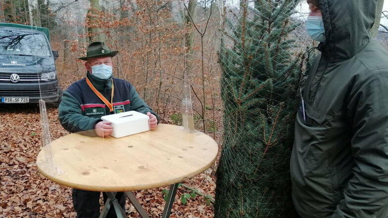 Revierförster Jens Lippmann kassiert im Wald hinter einer Plexiglasscheibe. Die 15-Kilometer-Regel reduzierte jedoch den Umsatz beim Weihnachtsbaum-Verkauf.