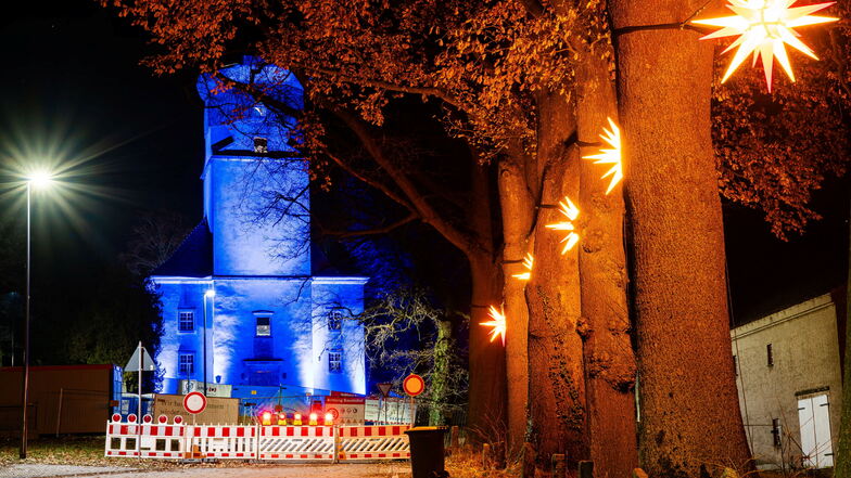 Ein imposantes Bild: Die abgebrannte Kirche wird  blau angestrahlt. Entlang des Weges zur Ruine leuchten Herrnhuter Sterne.