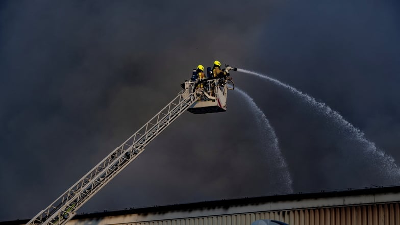 Dunkler Rauch steigt aus einem Betrieb in Neukölln. Dort brannte gepresstes Papier in einer Halle. Die Feuerwehr ist mit einem Großaufgebot vor Ort.