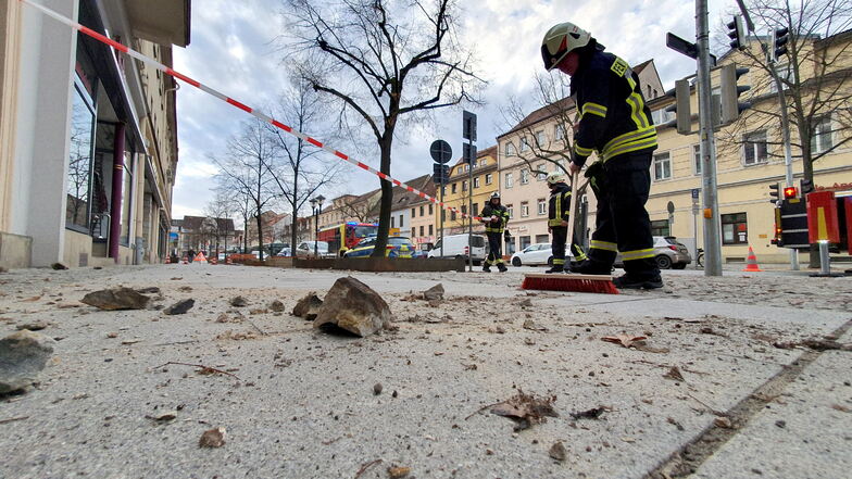 Ein Feuerwehrmann kehrt die runtergefallenen Steine vor dem Dürüm-Kebab-Haus Yaylak in der Breiten Straße in Pirna weg. Zum Glück war das Geschäft geschlossen, als die Brocken runterkamen.