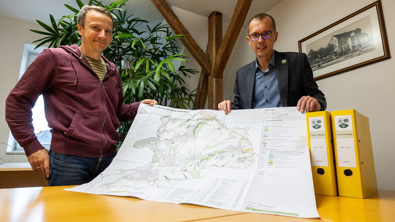 Rathausmitarbeiter Ronny Michalsky (li.) und Bürgermeister Heiko Wersig (parteilos) falten den Landschaftsplan für die Gemeinde Bannewitz aus.