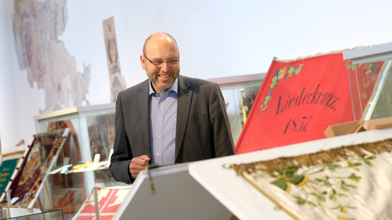 Gehörte zu den ersten Besuchern: Meißens Oberbürgermeister Olaf Raschke (parteilos) bewundert die kunstvoll gestickten Vereinsfahnen in der neuen Sonderschau des Museums.