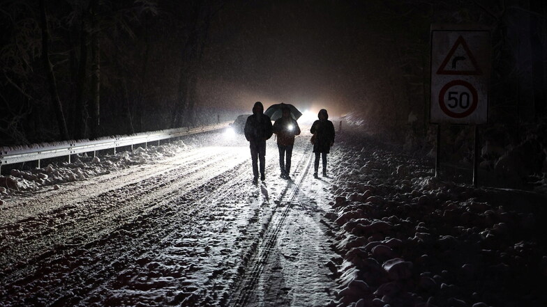Zu Fuß gehen Menschen über die verschneite Straße nach einem starken Wintereinbruch in Hessen.