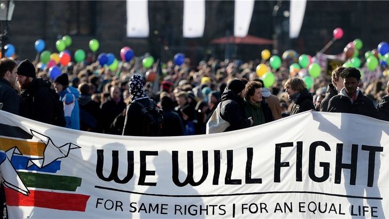 Teilnehmer tragen ein Transparent mit dem Spruch "Wir werden für gleiche Rechte für ein gleiches Leben kämpfen" auf dem Theaterplatz.