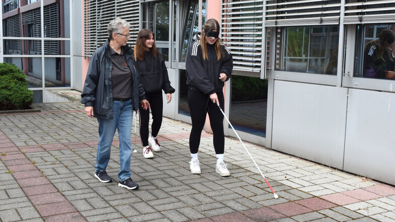 Die Rehalehrerin für Blinde und Sehbehinderte, Annedore Neigenfind vom BWS erklärt den angehenden Sozialassistentinnen Leonie (M.) und Lucie auf dem BSZ-Schulhof, wie der Langstock zu verwenden ist.