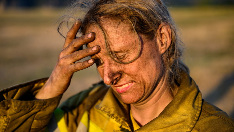 Julia Richardt, freiwillige Feuerwehrfrau bei dem Internationalen Katastrophenschutz Deutschland "@fire" steht nach dem Einsatz gegen die Waldbrände im Nationalpark Sächsische Schweiz auf einer Wiese.