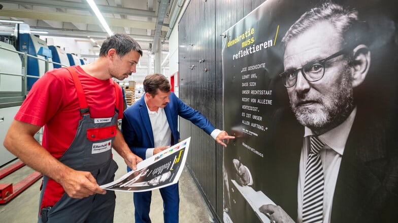 Druckereileiter Alexander Schmidt (l.) und Vorstand Stephan Ellerhold begutachten ein frisch bedrucktes Plakat. In der schwarzen Farbe ist der Text des Grundgesetzes, gespeichert in künstlicher DNA, enthalten.