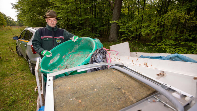 Revierförster Michael Blaß hat in seinem Anhänger gesammelten Sperrmüll im Wald bei Graupa verstaut. Ganz oben liegt eine Geschirrspülmaschine, die illegal entsorgt wurde.