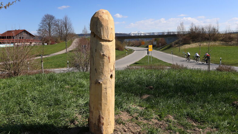 Ein rund hölzerner Penis steht in einem Kreisverkehr.