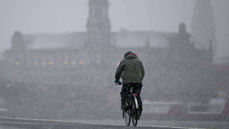 Schauriges Wetter in Dresden: Ein Radfahrer fährt bei stürmischem Schneefall auf dem Elberadweg vor der Altstadt entlang.