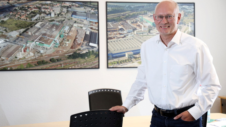 Uwe Reinecke ist Werksdirektor bei Feralpi Stahl in Riesa. In seinem Büro zeigen Luftbilder Ansichten des Stahlwerks.