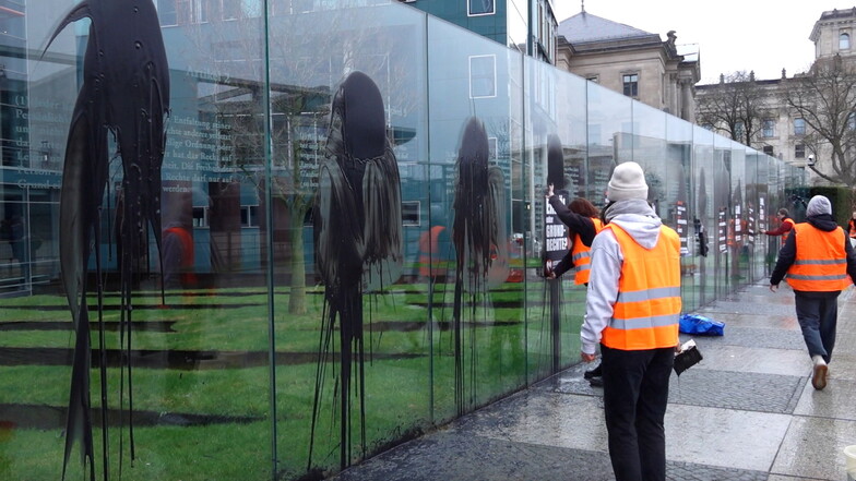 Anhänger der "Letzten Generation" beschmieren und plakatieren die gläserne Grundgesetz-Skulptur am Bundestag.